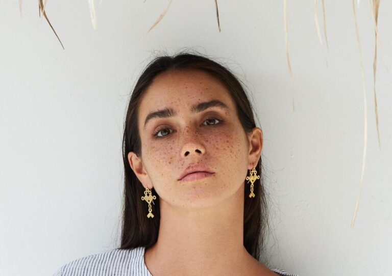 Symbolbild Sommersprossen-Tattoo: Frau mit Sommersprossen und goldenen Ohrringen