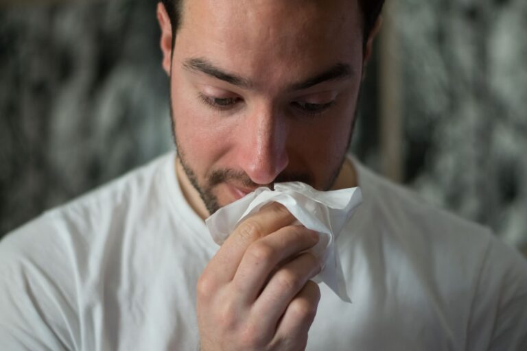 Symbolbild Allergisch auf Tattoofarbe: Mann putzt sich die Nase mit Taschentuch