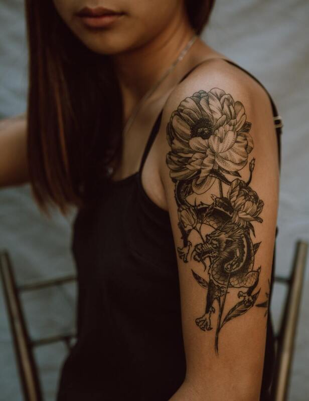 Symbolbild Cover-up Tattoos am Oberarm: Schwarzes Tattoo mit Drachenmotiv