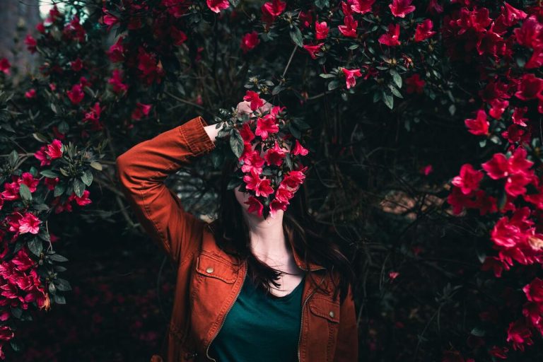 Symbolbild Cover up: Frau versteckt sich hinter Blumen