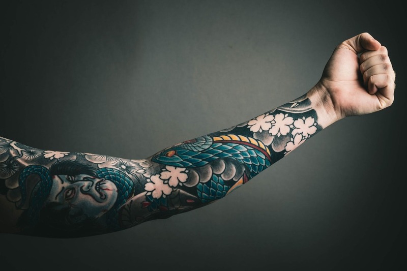 Symbolbild Cover-up Tattoos Oberarm: Bunt tätowierter Arm