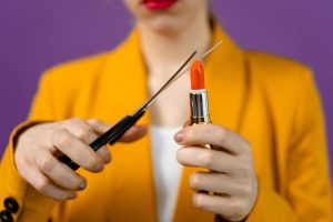 Symbolbild Permanent Make-up entfernen: Frau schneidet die Spitze eines Lippenstiftes ab